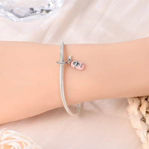 Detalle del dije de zapatilla de ballet en esmalte rosa sobre pulsera de cadena de plata