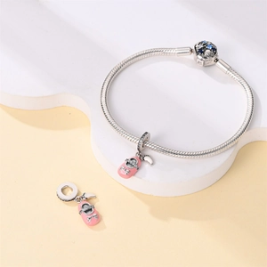 Detalle de pulsera de plata con zapato de bebé en esmalte rosa y cierre de piedra
