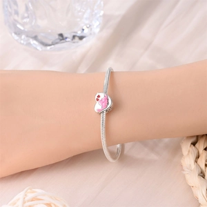 Pulsera de plata con colgante de corazón de esmalte rosa en la muñeca de mujer