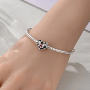 Silver open bangle featuring a heart charm with pink butterfly enamel and tiny zircons