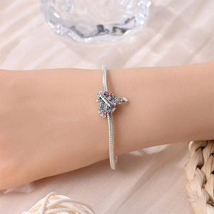 Detalle de una pulsera de dijes plateada con colgante de corazón grabado para el Día de la Madre