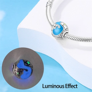 Dettaglio macro dello charm a globo luminoso con smalto blu e stelle su bracciale a serpente