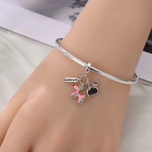 Silver charm bracelet with pink balloon dog, black handbag, and Lucky engraved pendant