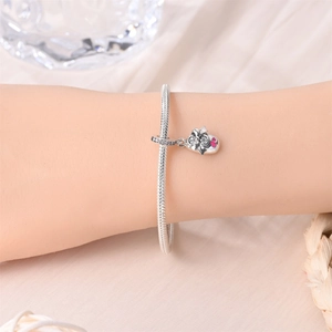 Primer plano de una pulsera de serpiente plateada con un colgante de calavera y corazones