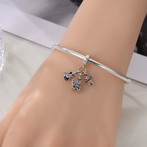 Detail of silver-plated bracelet with Eiffel Tower, guitar and butterfly charms on wrist