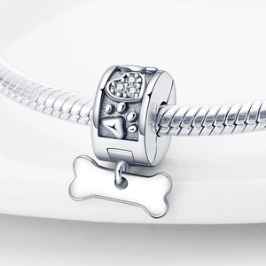 Dettaglio macro del charm in argento con zircone a cuore, zampa e osso su catena snake
