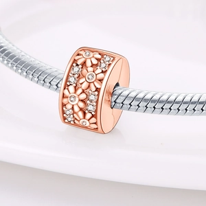 Dettaglio macro dello charm margherita in oro rosa con zirconi su catena a serpente