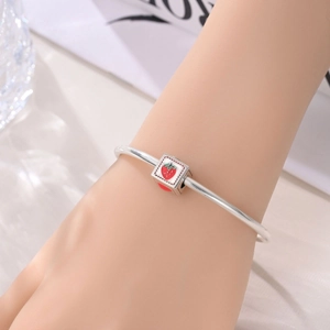Nahaufnahme eines Silberarmbands mit süßem Erdbeer-Charm und roter Emaille-Verzierung