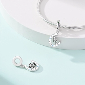Close-up of silver horseshoe charm with Luck engraving and green clover on snake chain