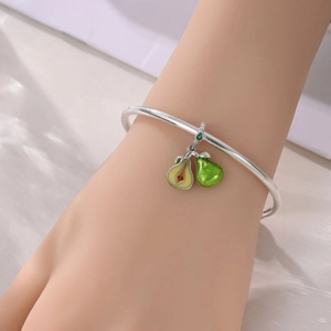 Primer plano de una pulsera de plata con dije de pera, purpurina verde y esmalte