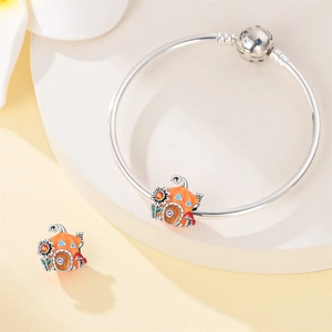Macro detail of pumpkin mushroom house charms on a silver bangle bracelet