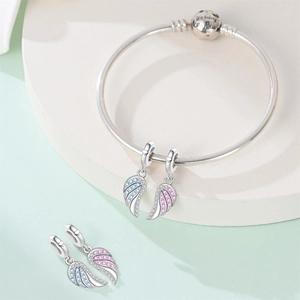 Close-up of wing heart puzzle charms and silver snake chain bracelet with engraving