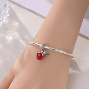 Detalle de una pulsera de plata con colgante de fresa roja y grabado Sweet