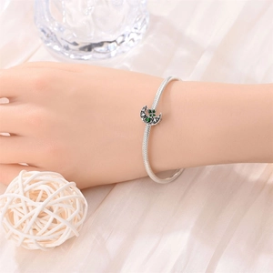 Silver bracelet with green four-leaf clover and crescent moon charm on wrist