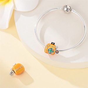 Detail of yellow enamel camera charm with zircon accents on a silver bangle bracelet