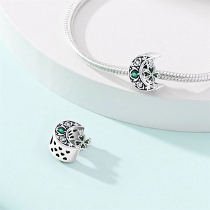 Silver horseshoe moon charm with green gems and clover design on a snake chain bracelet