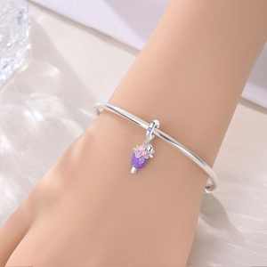 Primer plano de una pulsera de plata con colgante de gato esmaltado en la muñeca