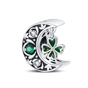 Macro detail of silver crescent moon charm with green clover and vine engraving