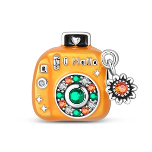 Macro detail of silver camera charm with orange enamel and colorful crystals