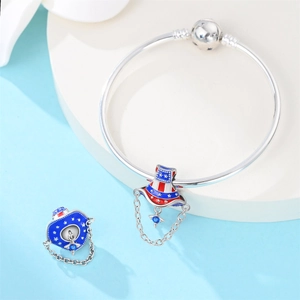 Detailed view of silver charm bracelet featuring a patriotic enamel hat pendant with blue gem