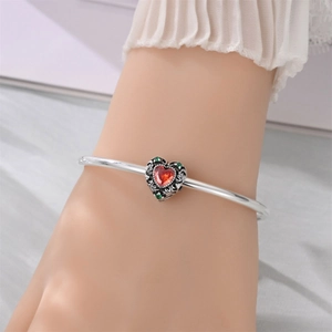 Detailed view of silver open bangle featuring a vintage red heart pendant with engravings