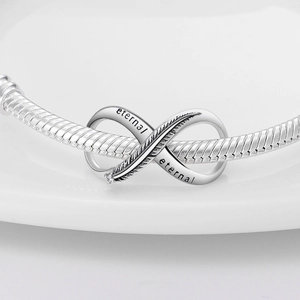 Macro view of silver feather charm with infinity symbol and eternal engraving detail