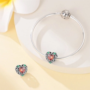 Detailed macro view of heart charm with red gemstone on silver snake chain bracelet