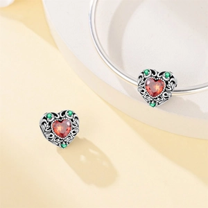Detailed view of vintage heart pendant with red stone and green accents in silver finish