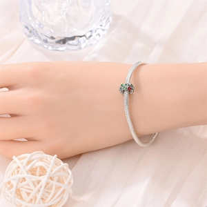 Silver snake chain bracelet with green and red enamel lucky clover charm detail