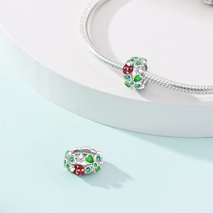 Macro detail of a 925 silver charm with green leaves and a red ladybug on a bracelet