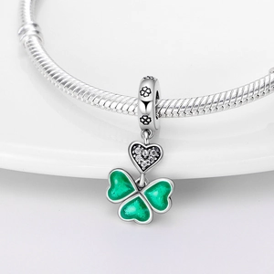 Détail macro du charm trèfle en émail vert et perle cœur en zircone sur chaîne en argent