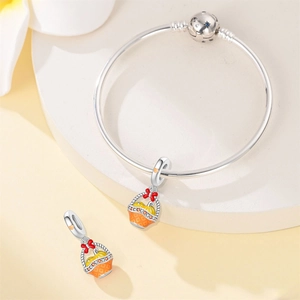 Macro detail of pumpkin basket pendant on silver bangle with vibrant enamel finish