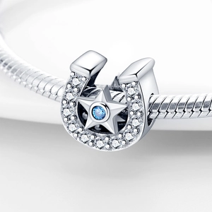 Macro shot of horseshoe charm with blue gemstone and stars on silver snake chain