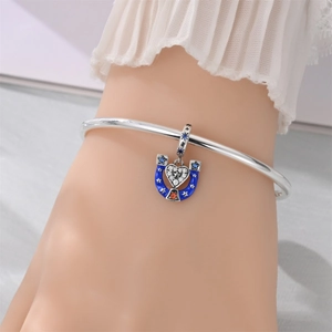 Detailed view of silver horseshoe charm with blue enamel stars and a crystal heart pendant