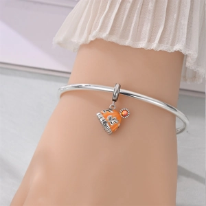 Detailed macro view of orange enamel fall hat charm with snowflake and Fall lettering