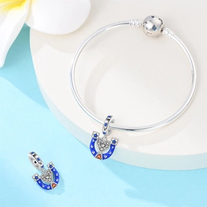 Detailed shot of silver snake chain bracelet with blue enamel horseshoe charms and crystals