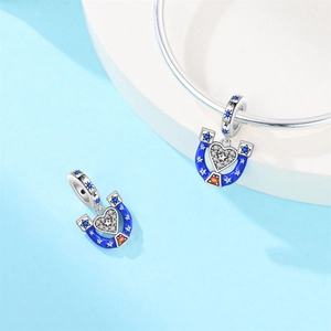 Macro detail of silver horseshoe and heart charm with blue enamel and star zirconias