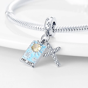 Silver sun and cross charms on a snake chain bracelet with blue enamel and yellow zircon