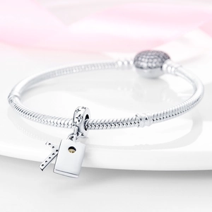 Macro view of silver snake chain bracelet with CZ pavé clasp and K letter charm