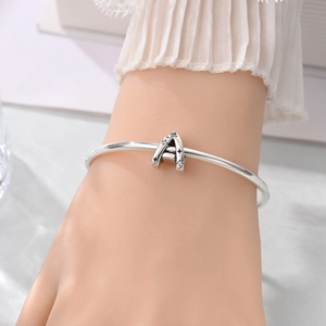 Close-up of a silver charm bracelet featuring a sparkling zircon-studded letter A pendant