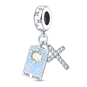Macro detail of silver sun tarot charm and sparkling cross pendant for DIY jewelry