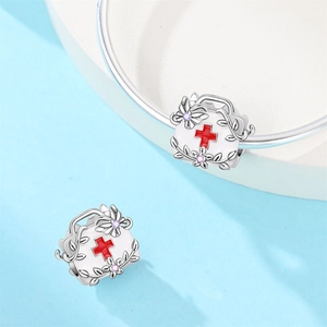 Detailed macro view of silver medical first aid kit charm with red cross and zircon stones