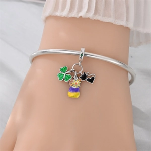 Close-up of silver bangle featuring colorful clover and cowboy charms on a wrist