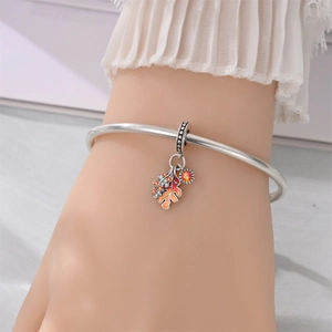 Macro shot of silver bracelet featuring a maple leaf pendant with colorful enamel and zircon