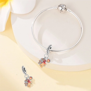 Detail of silver bracelet with enamel maple leaf and acorn charms and engraved clasp