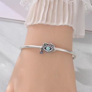 Detail of silver-plated evil eye charm bracelet with turquoise enamel and gemstone pendants