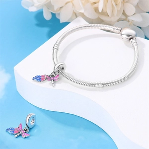 Detailed shot of dragonfly wing charm with pink and blue gradient on snake chain bracelet
