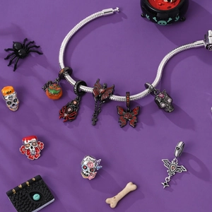 Halloween zilveren bedelarmband met pompoen en schedel hangers op een paarse achtergrond