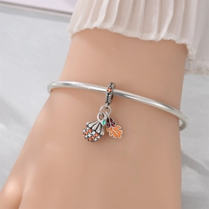 Detail of silver bracelet with acorn and maple leaf charms in warm autumn colors