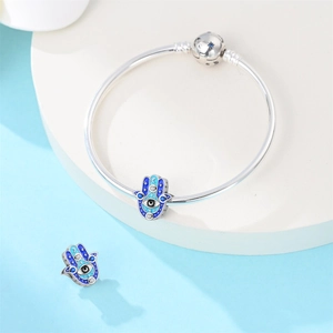 Macro view of blue Hamsa Hand charms and evil eye details on silver snake chain bracelet